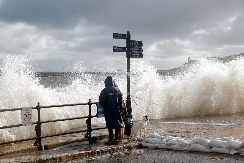 People watch as waves crash up on the promenade during storm Alex, in Swanage, Dorset, Britain. REUTERS/Andrew Couldridge  